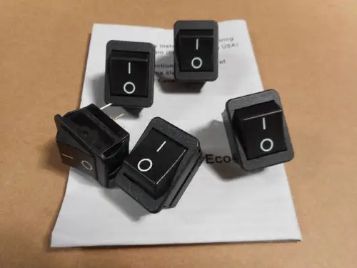 Fünf schwarze Hauptschalter mit I/O-Symbolen, auf einem Untergrund liegend, gemeinsam dargestellt. Remeha ist als Marke erkennbar.